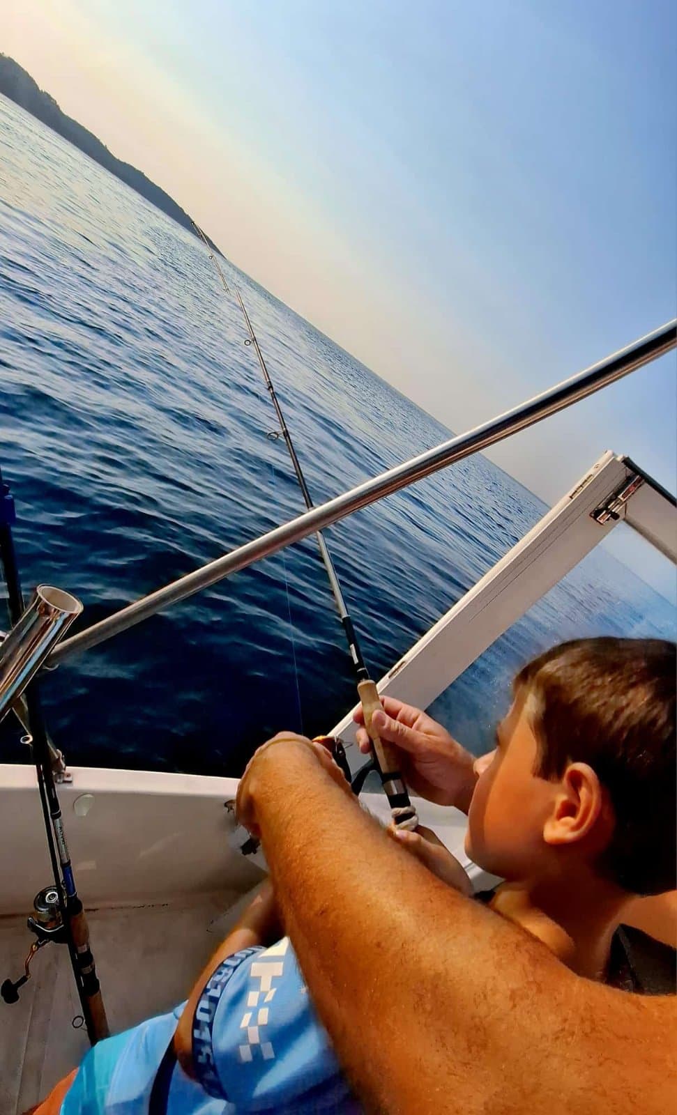 Young guest fishing from the boat