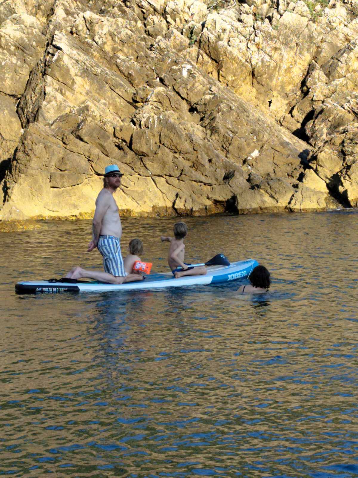 Guest paddleboarding below rocky cliffs
