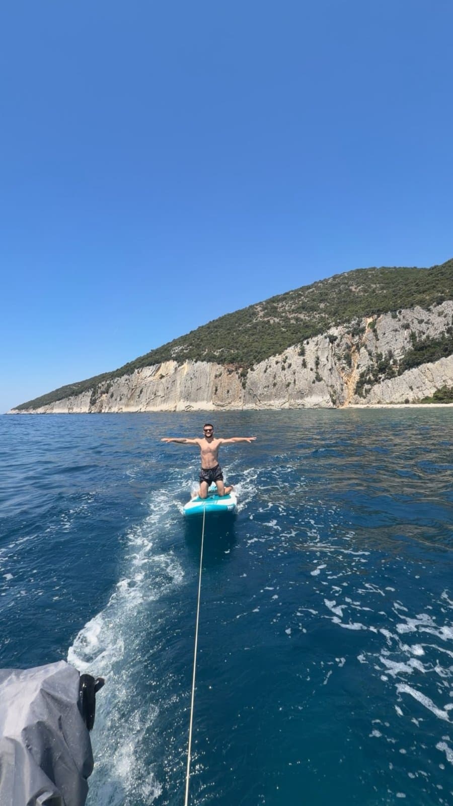 Paddleboard rider towed across bright blue water